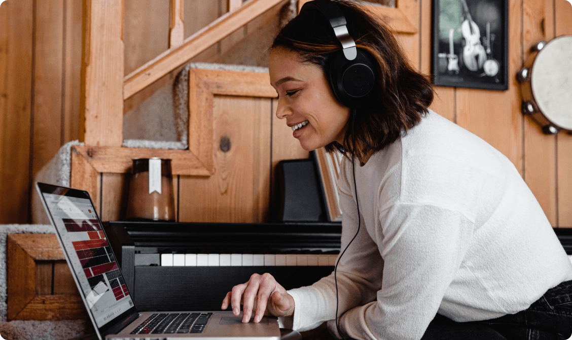 Woman in over-ear headphones streaming a podcast episode on a laptop
